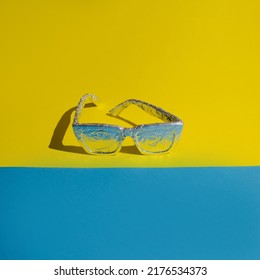 Concept Made With Sunglasses Wrapped In Aluminum Foil On A Blue And Yellow Background. The Idea Of ​​maximum Sun Protection And Insulation.