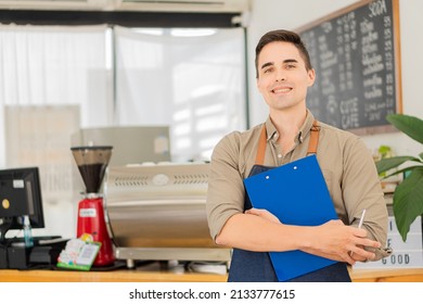 Concept Male Professional Waiter In Black Apron Holding Menu And Smiling While Inviting Guests To Bakery The Shopkeeper Stood At The Entrance To The Cafeteria Showing Generosity.