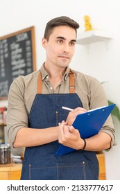 Concept Male Professional Waiter In Black Apron Holding Menu And Smiling While Inviting Guests To Bakery The Shopkeeper Stood At The Entrance To The Cafeteria Showing Generosity.