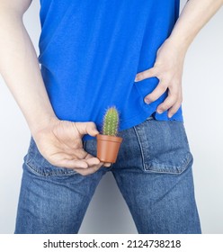 Concept. A man holds a cactus as a symbol of rectal pain. Varicose veins of the lower intestine. Pain in the rectum, hemorrhoids and pain in the excretory system of the body. Proctology