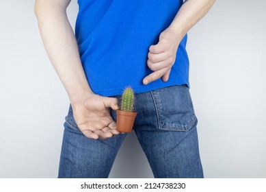 Concept. A man holds a cactus as a symbol of rectal pain. Varicose veins of the lower intestine. Pain in the rectum, hemorrhoids and pain in the excretory system of the body. Proctology