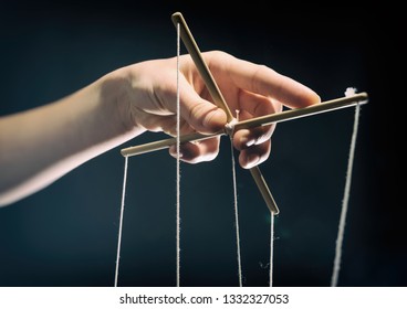 Concept of manipulation. Hand holds strings for manipulation. On dark background.