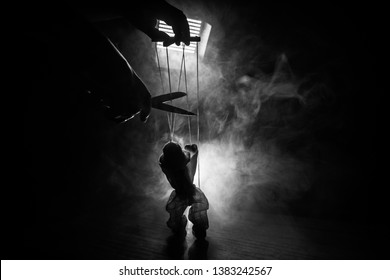 Concept of manipulation. Hand holds strings for manipulation. The hand controls the puppet strings on a dark foggy background. Selective focus