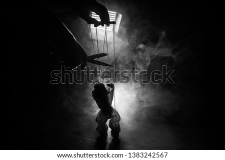 Concept of manipulation. Hand holds strings for manipulation. The hand controls the puppet strings on a dark foggy background. Selective focus