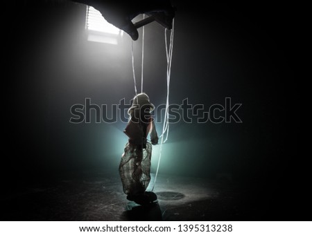 Concept of manipulation. Hand holds strings for manipulation. The hand controls the puppet strings on a dark foggy background. Selective focus