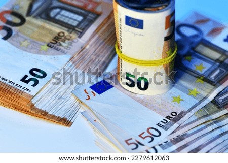 Concept of many euros: a pile of rolled 50-euro bills lying on a white background