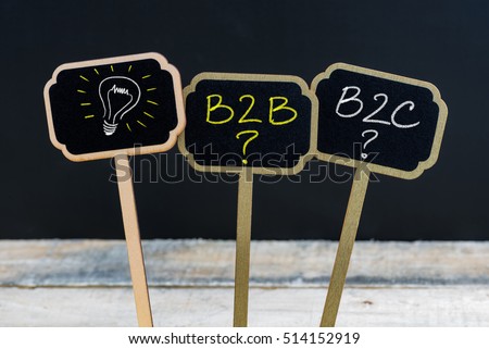 Concept message B2B as Business To Business, B2C as Business To Consumer and light bulb as symbol for idea written with chalk on wooden mini blackboard labels,  chalkboard and wood table in background
