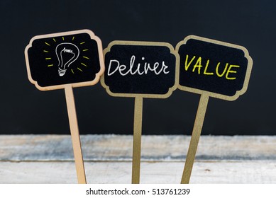 Concept Message DELIVER VALUE And Light Bulb As Symbol For Idea Written With Chalk On Wooden Mini Blackboard Labels, Defocused Chalkboard And Wood Table In Background