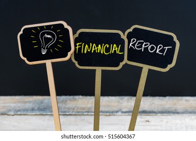 Concept message FINANCIAL REPORT and light bulb as symbol for idea written with chalk on wooden mini blackboard labels, defocused chalkboard and wood table in background