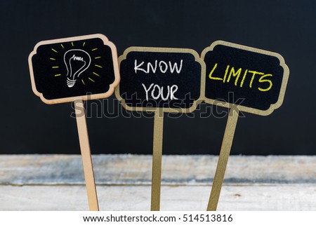 Concept message KNOW YOUR LIMITS and light bulb as symbol for idea written with chalk on wooden mini blackboard labels, defocused chalkboard and wood table in background