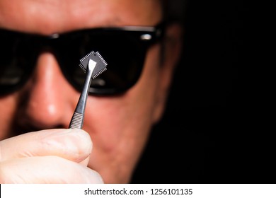 The Concept Of Military Artificial Intelligence And Machine Learning .A Man In Black Glasses Holds A Microchip. 