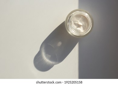 Concept of minimalist skincare routine and sun protection. Top down view of a jar of moisturizer with a contrasting shadow.