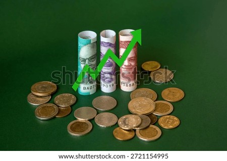 Concept of minimum wage increase using Colombian peso bills and coins and an upward arrow. Living minimum wage.