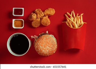 Concept of mock up burger, potatoes, sauce, chicken nuggets and drink on red background. Copy space for text and logo.