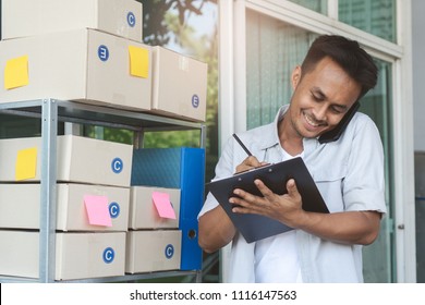 Concept Modern New Asian Entrepreneur. E-commerce Business Owner Calling To Supplier To Confirm Order And Reviewing Checklist Of Customer Address Before Sent Box Of Product By Parcel Post.