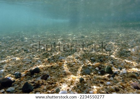 The concept of natural backgrounds and textures. Small pebbles and stones at the bottom of the Aegean Sea. Underwater photo, selective focus. Bodrum, Mugla province, Turkey, Europe.