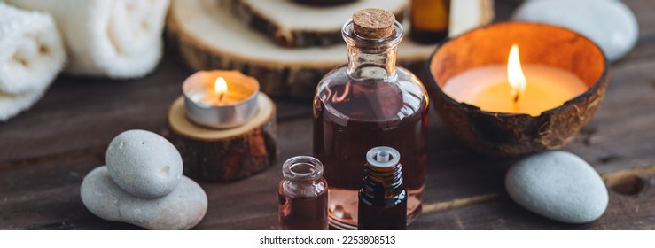 Concept of natural essential organic oils, Bali spa, beauty treatment, relax time. Atmosphere of relaxation, pleasure. Candles, towels, dark wooden background. Alternative oriental medicine. Banner - Shutterstock ID 2253808513