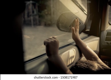 Concept Negligence, Forgetting Small Children In The Car :  Little Girl Is Trapped Inside The Car Alone, Using The Glass Door Handle Of The Car And No One Is Paying Attention, Bowing In Sadness.