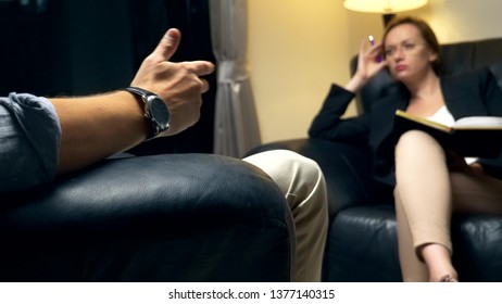 concept of negotiation, psychological counseling. A woman with a notebook communicates with a successful man. sitting in the evening in the office in a leather chair. - Powered by Shutterstock