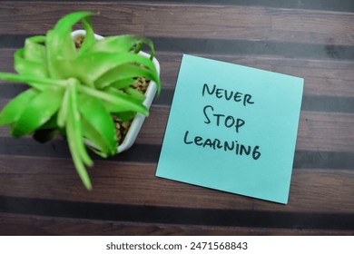 Concept of Never Stop Learning write on sticky notes isolated on Wooden Table.