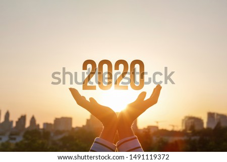The concept new 2020 year. Hands show 2020 on the background of sunset.