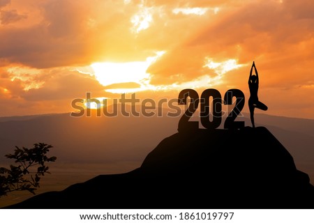 Concept of New 2021.silhouette of woman yoga stand on the mountain with 2021 year.