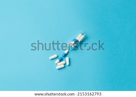 The concept of a new drug. The pills with the medicine fall out of the bottle. Pills for the treatment of the disease are on a blue background. Advertising concept. View from above. Copy space