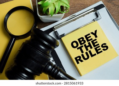 Concept of obey the rules write on sticky notes isolated on Wooden Table.