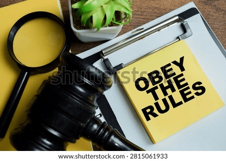 Concept of obey the rules write on sticky notes isolated on Wooden Table.