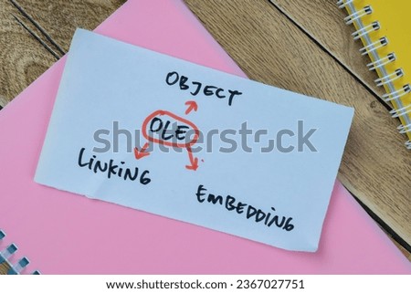 Concept of OLE - Object Linking Embedding write on sticky notes isolated on Wooden Table.
