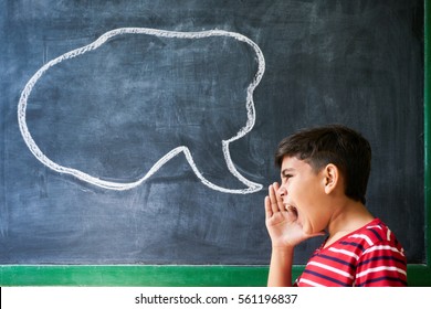 Concept On Blackboard At School. Young People, Student And Pupil In Classroom. Hispanic Boy Screaming In Class With Drawing Of Cloud On Blackboard. Portrait Of Frustrated Male Child