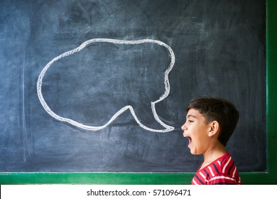 Concept On Blackboard At School. Young People, Student And Pupil In Classroom. Hispanic Boy Screaming In Class With Drawing Of Cloud On Blackboard. Portrait Of Frustrated Male Child