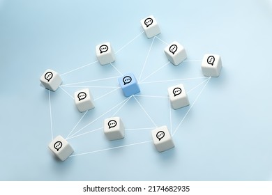 The concept of online communication or social networks. White cubes with speech bubbles connected by lines on a blue background.