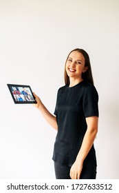 Concept Of Online Communication. A Woman Is Using App At Digital Tablet For Video Call For Several People At Same Time Together. She Looks At Camera With A Smile. Isolated On White Background