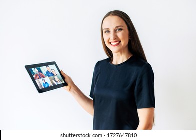 Concept Of Online Communication. A Woman Is Using App At Digital Tablet For Video Call For Several People At Same Time Together. She Looks At Camera With A Smile. Isolated On White Background