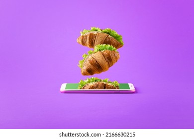 Concept of online food delivery with copy space. Flying sandwiches from a smartphone on a purple background.  - Shutterstock ID 2166630215