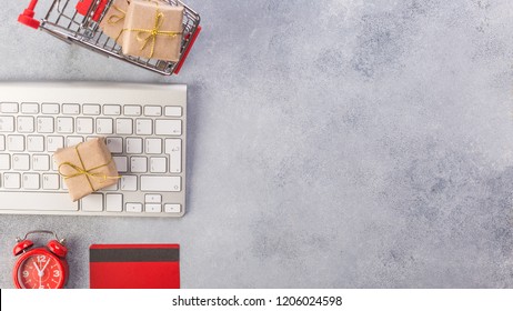 Concept online shopping buying presents. Red credit card, keyboard and christmas presents on grey table flat lay, copy space. Business christmas holidays concept, holiday gift online shopping concept.
