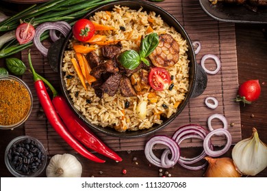 The concept of oriental cuisine. Homemade Uzbek pilaf or plov from lamb served in cast iron cookware. Copy space.