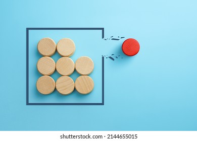 Concept of overcoming barriers, goal, target. Red wooden cube breaking through obstacle on blue background