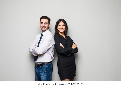 Concept Of Partnership In Business. Young Man And Woman Standing Back-to-back With Crossed Hands Against Gray