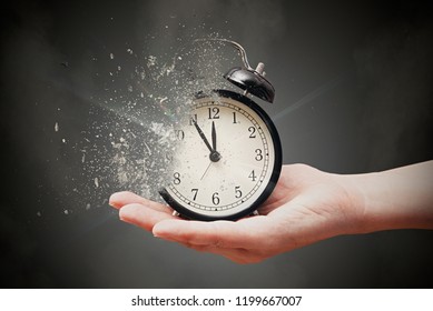 Concept of passing away, the clock breaks down into pieces. Hand holding analog clock with dispersion effect