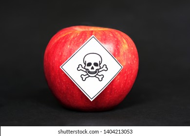 Concept Of Pesticide Residues In Agricultural Food Products Dangerous To Humans, Showing A Red Apple With Poison Symbol Sticker On Black Background