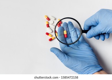 Concept - pharmaceutical testing, drug testing, magnifying glass, pills on a white background. Anti-Doping Control.