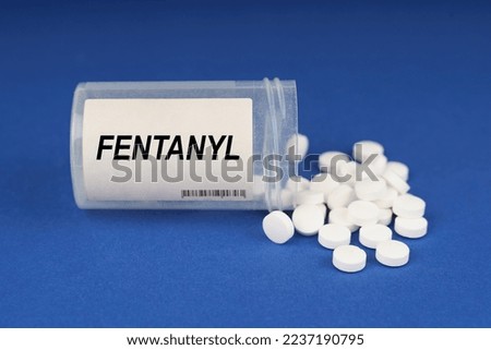 The concept of pharmacology and health. On a blue surface are pills and a dusty jar with the inscription - Fentanyl