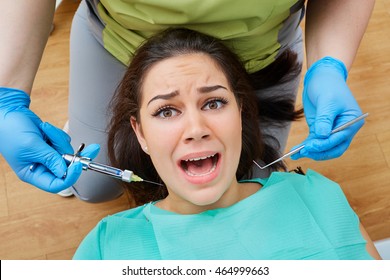 Concept Phobia Dentist, Dentistry, Dental, Instruments, Dental Clinic. Young Woman Treats The Tooth The Dentist With Open Mouth Afraid Of Toothache, Frightened Eyes, The Horror On His Face.