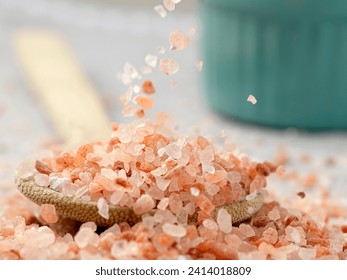 Concept photo of coarse himalayan pink salt falling down onto a wooden spoon. - Powered by Shutterstock