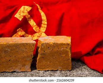 The concept of photo of dissolution of the Soviet Union, the Cold War, communism, totalitarianism, decommunization. Cracked brick next to the USSR flag.