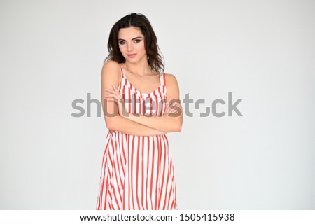Concept photo portrait of a cute pretty beautiful brunette girl with excellent makeup in a striped dress on a white background. In different poses with emotions.
