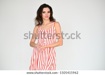 Concept photo portrait of a cute pretty beautiful brunette girl with excellent makeup in a striped dress on a white background. In different poses with emotions.
