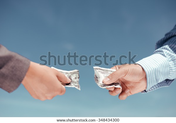 Concept photo of two hands pulling apart\
money banknote on light blue background\
